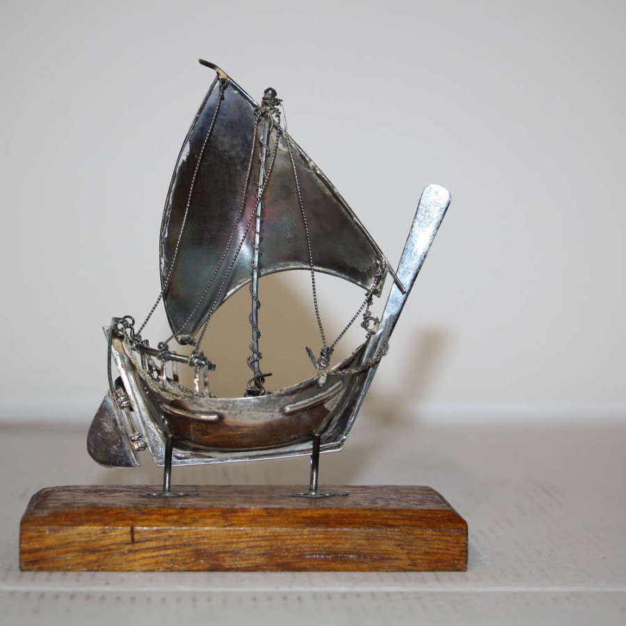 A small silver white metal boat on a stand,14cm ht x 11cm in width.
