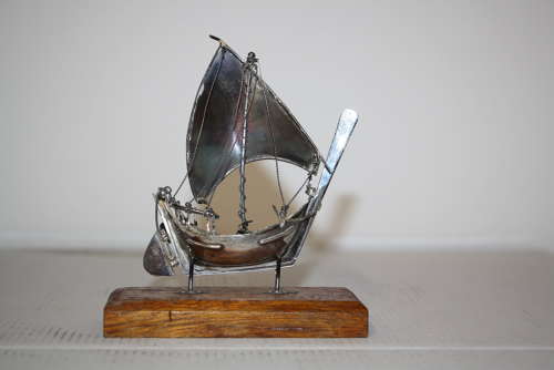 A small silver white metal boat on a stand,14cm ht x 11cm in width.