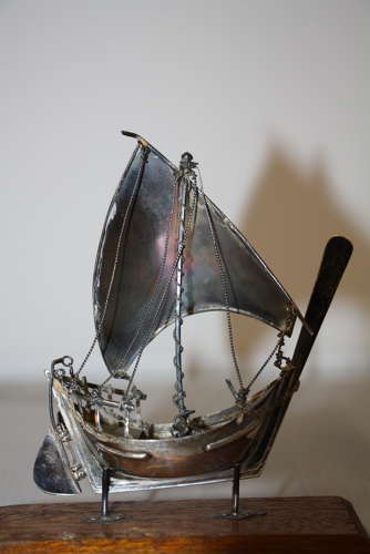 A small silver white metal boat on a stand,14cm ht x 11cm in width.