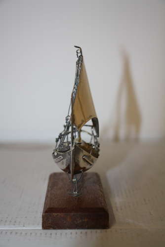 A small silver white metal boat on a stand,14cm ht x 11cm in width.