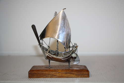 A small silver white metal boat on a stand,14cm ht x 11cm in width.